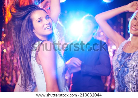 Joyful girls and guys dancing in night club