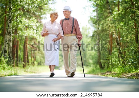 Happy seniors taking a walk in the park on sunny day