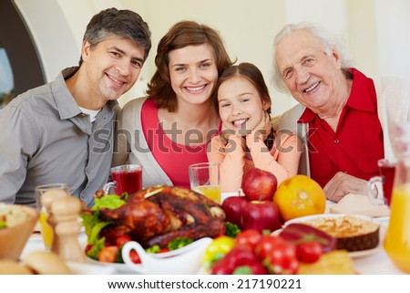 Happy family of four sitting at festive table on Thanksgiving day