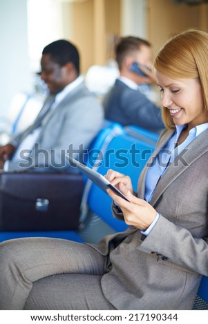 Female employee networking in airport with two men sitting on background