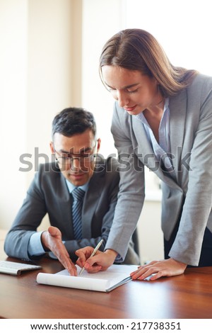 Businessman explaining to his secretary how to fill in the paper in office
