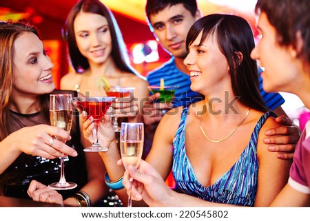 Cheerful girls and guys with martini and champagne having fun at party