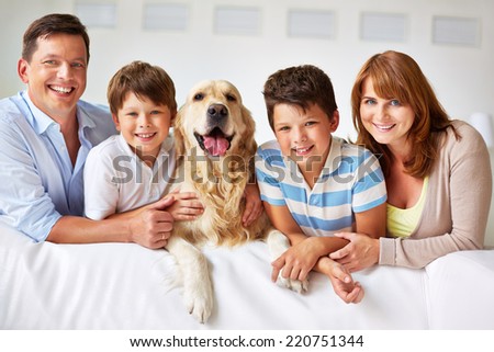Smiling family with thoroughbred dog looking at camera