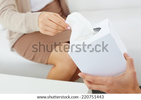 Close-up of patient hand taking paper tissue out of box being offered by her doctor