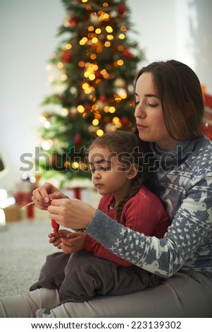 Pretty female showing her cute daughter how to knit