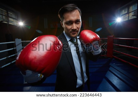 Strong and confident businessmen in suit and boxing gloves looking at camera