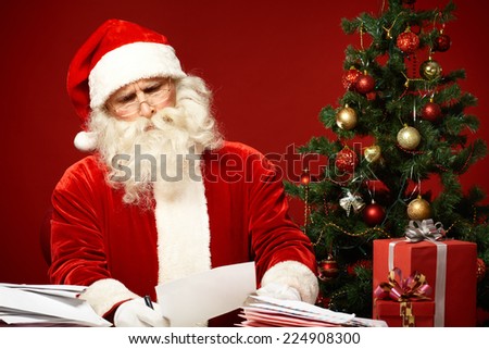 Portrait of confused Santa Claus reading letter
