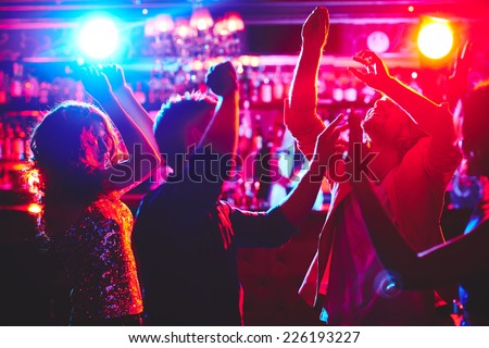 Group of dance lovers enjoying disco in nightclub