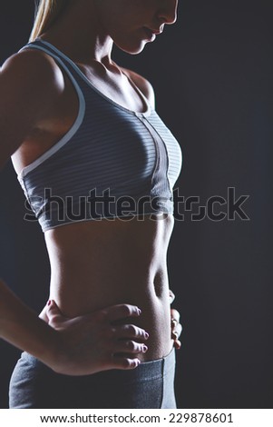Body of slim female in activewear keeping her hands on waist