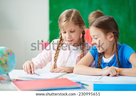 Cute girls sitting at drawing lesson and discussing ideas of picture