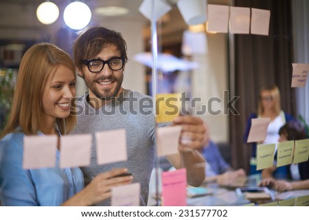 Male and female co-workers reading reminders in office