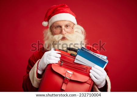 Santa Claus with red leather suitcase and airline tickets