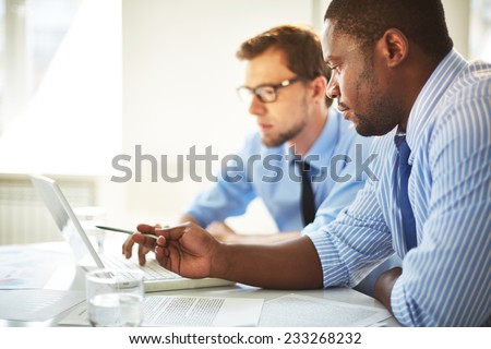 Man pointing at laptop for his colleague
