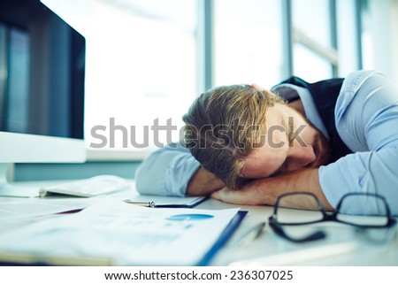Young businessman sleeping by his desk in office