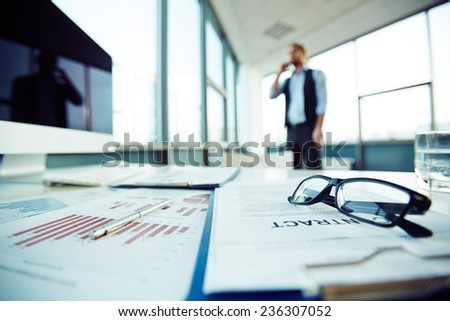 Business objects on desk with businessman calling on background