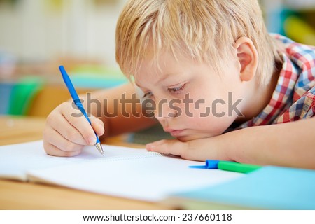 Cute learner making notes in copybook at lesson