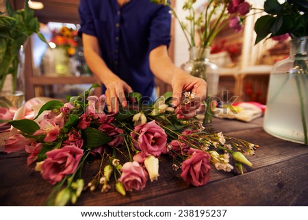 Female florist separating roses from small white flowers in workshop