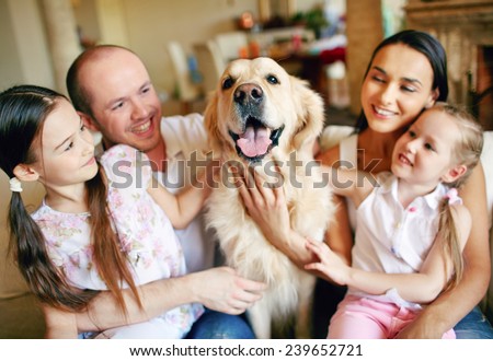 Cute girls and their parents cuddling dog