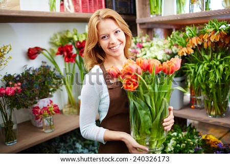 Young florist with fresh red tulips in the shop