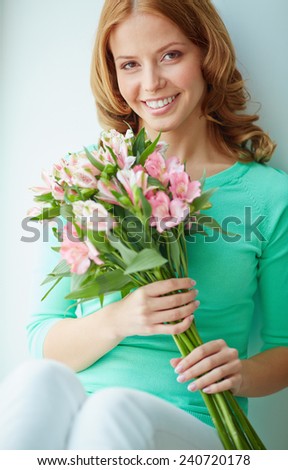 Happy girl with bunch of pink lilies looking at camera