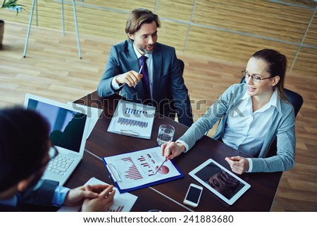 Three business people discussing financial report of one worker