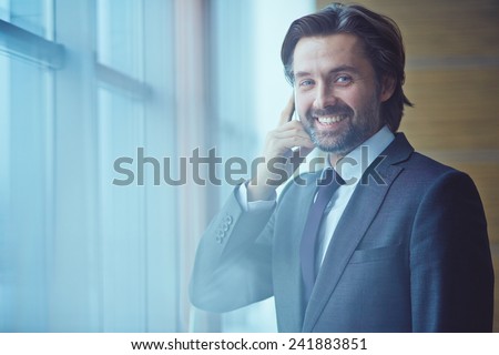 Man with mobile phone smiling and looking at camera