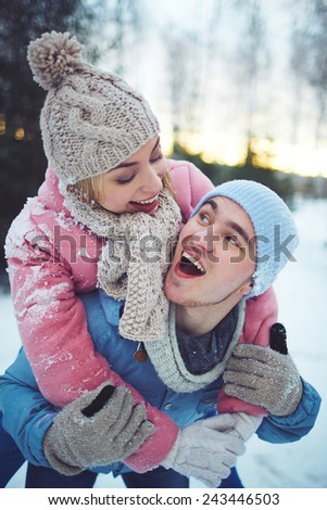 Joyful guy and girl in winterwear having fun