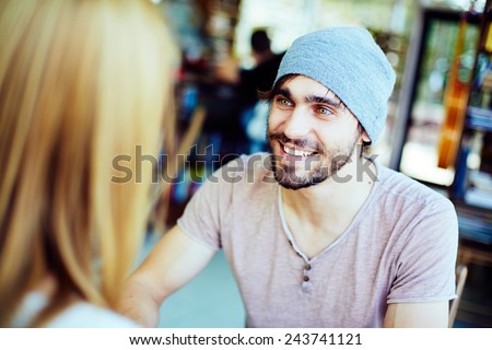 Young guy looking at his girlfriend while listening to her