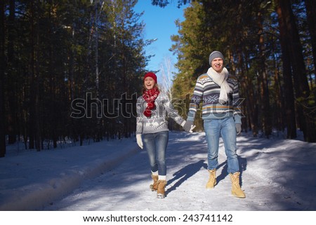 Amorous and ecstatic couple taking walk in winter forest