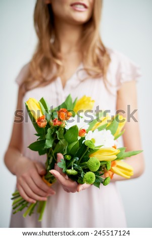 Young female holds bunch of fresh roses, tulips and chrysanthemums