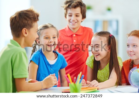 Friendly boys and girls talking and laughing at break in school