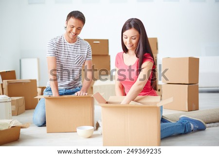 Young couple unpacking boxes in their new flat