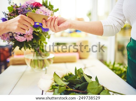 Female florist taking credit card from buyer hand