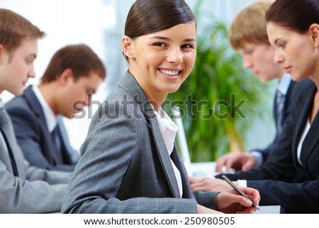Successful businesswoman looking at camera on background of working colleagues