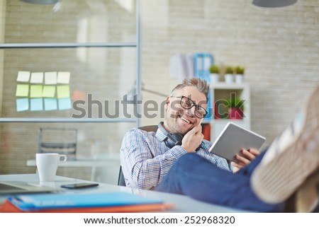 Happy young man speaking on cellphone while using touchpad