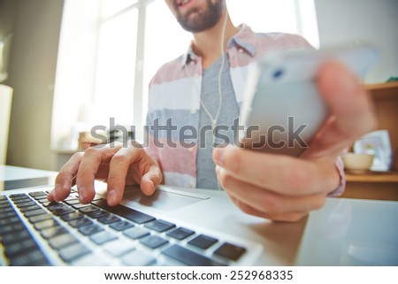 Young man using multi-media gadgets in office