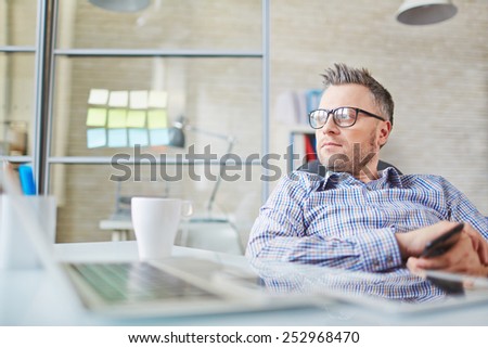 Calm businessman in eyeglasses sitting in office