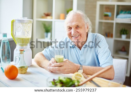 Senior man with glass of fruit smoothie looking at camera