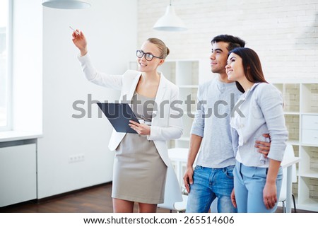 Pretty realtor consulting young couple about buying flat
