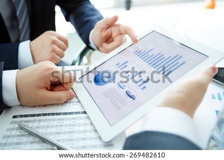Electronic document in touchpad and hands of businessmen during discussion of data