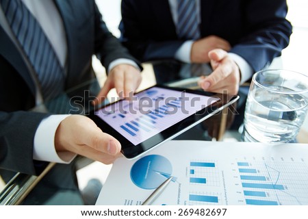 Hands of male employees discussing electronic document at workplace
