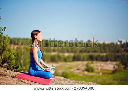 Meditating woman practicing yoga outdoors