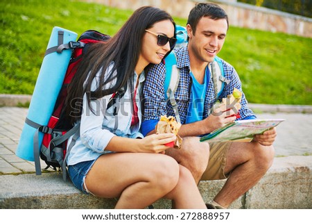 Young man and woman with rucksacks and map choosing travel route