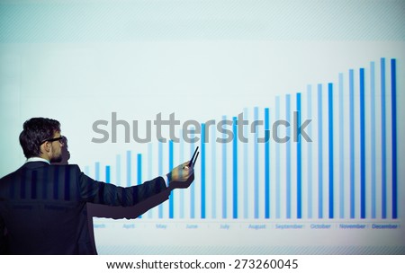 Rear view of businessman explaining chart on the wall