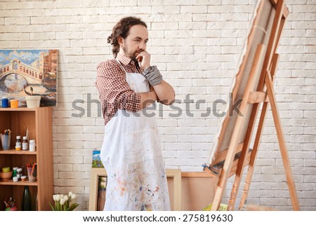 Young artist looking at canvas in studio