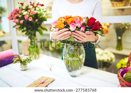 Female florist holding fresh roses in vase