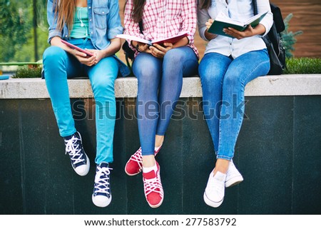 Modern teen girls reading outside