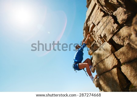 Young man climbing on top of rock