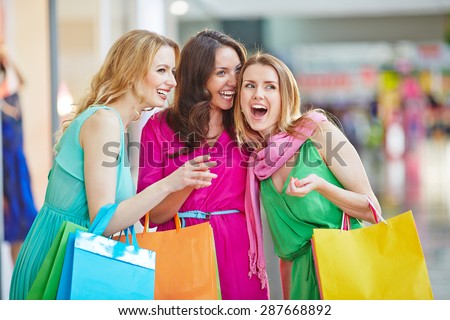 Charming shopaholics with paperbags discussing something the saw in the mall