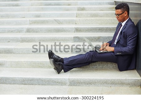 Young businessman using laptop while sitting on stairs